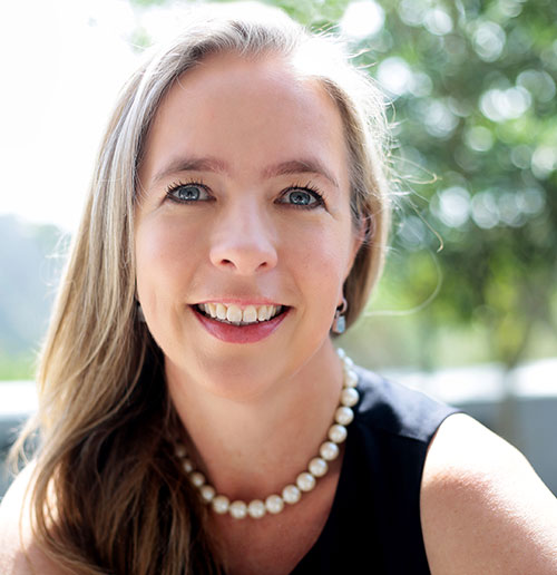 Julia Phelan smiling, wearing a black shirt and pearls