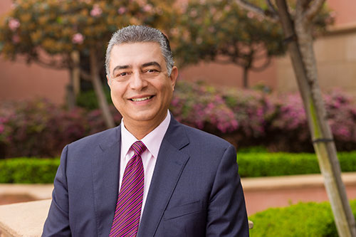 Shaw Ardalan standing in a park, smiling, dressed in a suit